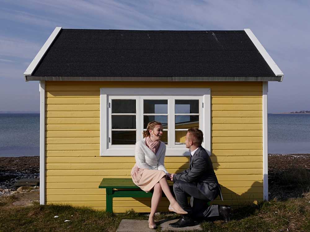 Couple d'amoureux devant une cabane sur la plage à Aero au Danemark