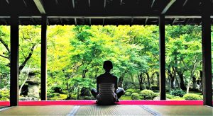 Femme qui médite dans un temple devant un jardin japonais