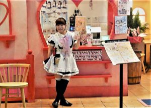 Une maid qui attire les clients devant un café à Tokyo.