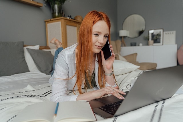 femme entrain de travailler sur son lit avec son ordinateur portable
