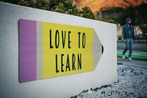 Panneau directionnel en forme de crayon avec la mention "Love to learn"