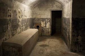 Pièce allumée du bunker situé dans le parc El Capricho à Madrid. Lit en béton et porte ouverte donnant sur une autre pièce.