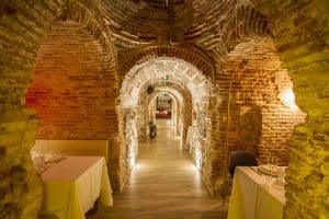 Cave à vins-restaurant à Madrid avec murs en pierre et tables dressées.