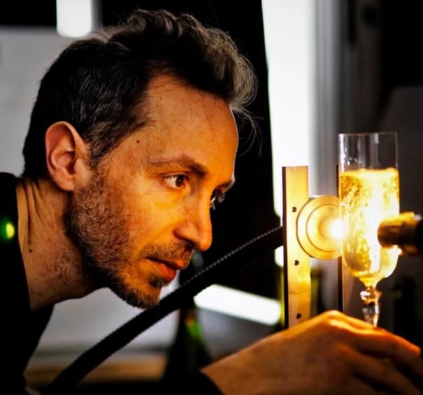 Visage du physicien Gérard Liger-Belair en train d'analyser les bulles d'un verre de champagne avec un appareil de mesure
