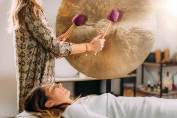 Lors d'un bain de gong, une femme allongée profite des bienfaits des puissantes vibrations sonores.