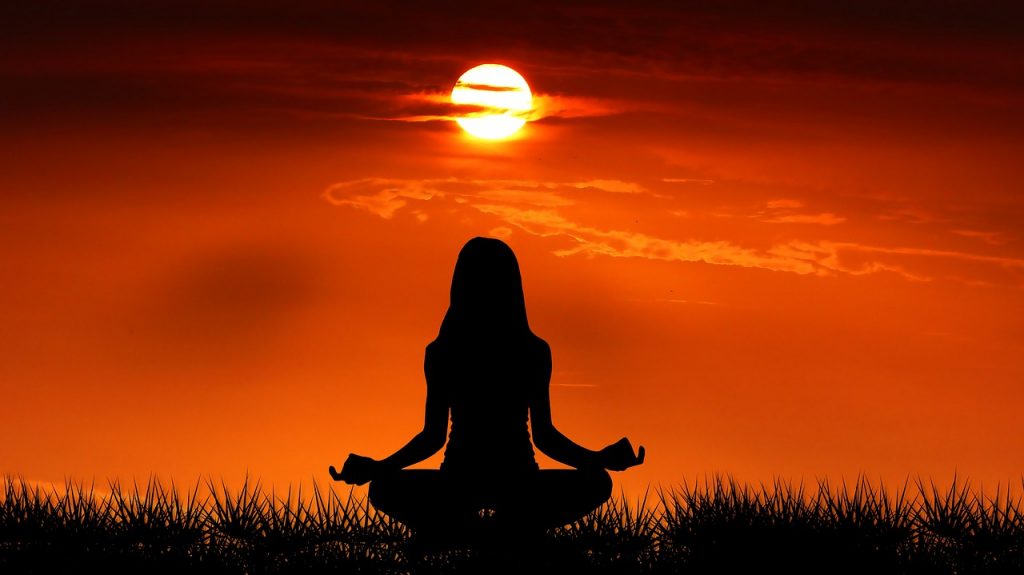 Jeune femme pratiquant le yoga en pleine nature sous un magnifique lever de soleil.