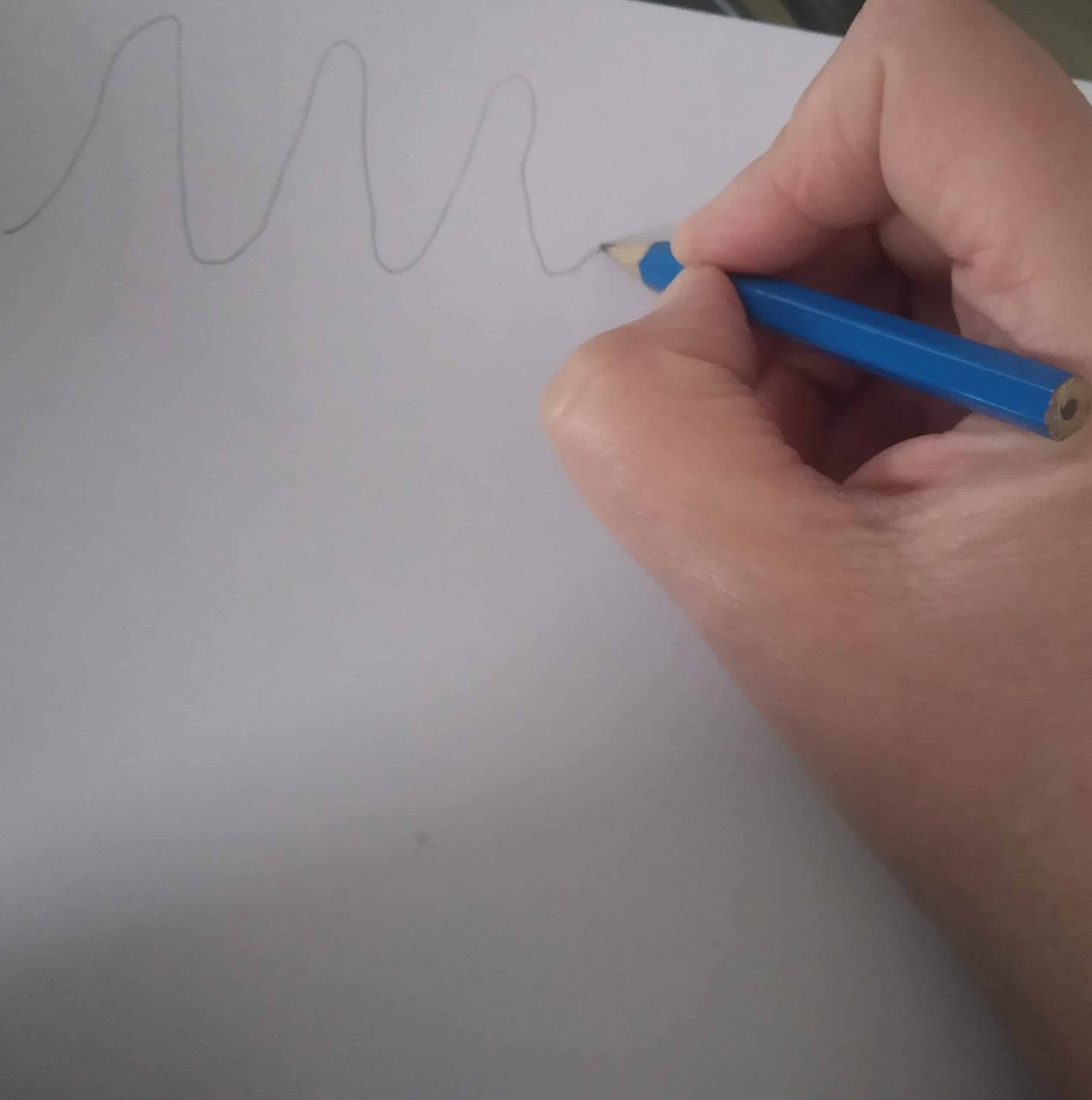 Une main tenant un crayon et traçant des vagues