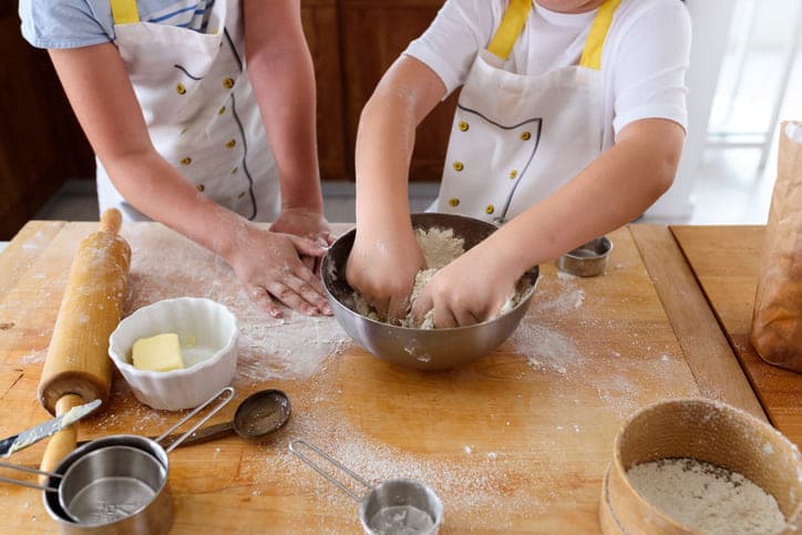 Les mains de deux enfants en train de préparer un gâteau