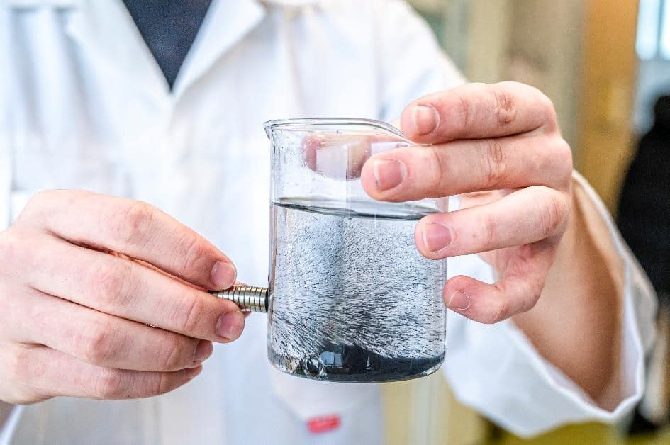 Procédé de magnétisation du plastique testé en laboratoire. Les microparticules présentes dans l'eau contenue dans le récipient sont attirées par des aimants.