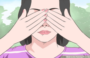 Femme pratiquant le palming, avec ses mains posées sur les yeux, utile en cas de fatigue visuelle.