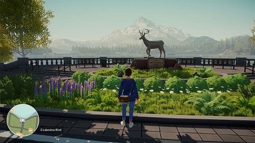 Capture d'écran du jeu Lake. Une femme de dos regarde une statue de cerf entourée de plantes. En arrière plan, on voit une montagne enneigée. 