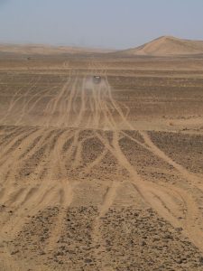 Deux 4×4 foncent en hors piste dans l'immensité d'un désert mi-sableux, mi-rocailleux. 