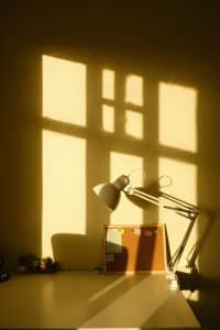 Reflets du soleil sur un bureau sur lequel est posé une lampe à bras articulé