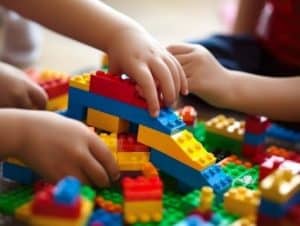 Plusieurs mains d'enfants interagissent pour élaborer une construction en Lego. Ces enfants développent ainsi la logique et leur relation à l'espace. Ces activités contribuent à les éveiller aux mathématiques.