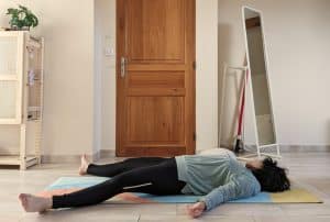 Personne réalisant la posture de yoga du savasana.