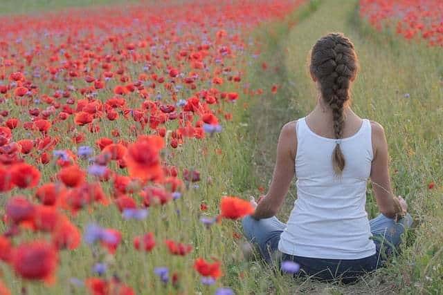 Femme qui médite dans un champ de coquelicots