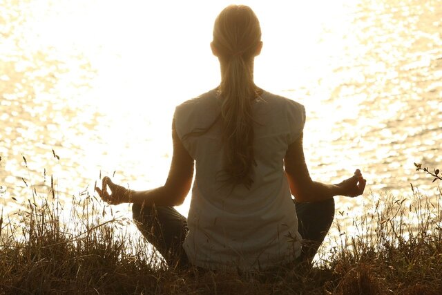 Femme pratiquant la méditation au bord de l'eau