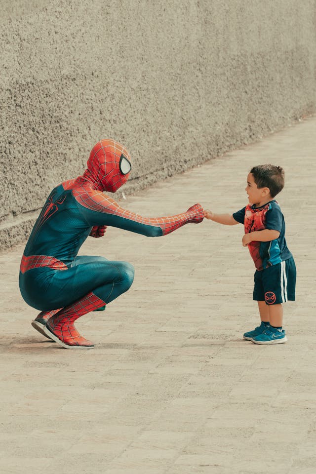 s expatrier en famille et se transformer en super heros. un papa et son enfant deguises en spiderman dans la rue.